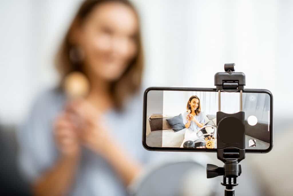 A woman recording a video blog or vlog using a smartphone mounted on a tripod, indoors in a bright, modern living space, showcasing professional web design services in Durham Region.