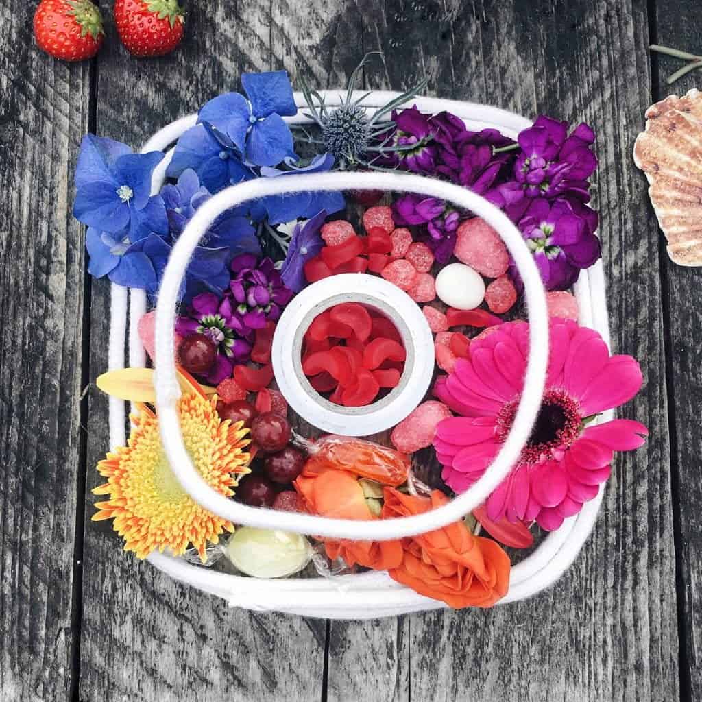 Brightly colored flower arrangement with assorted flowers, berries, and decorative elements on a rustic wooden surface.