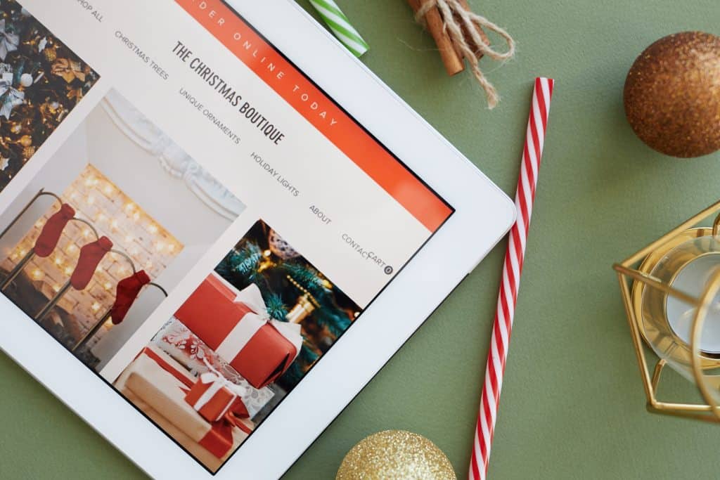 Elegant Christmas gift shopping website on a tablet with holiday decor, showcasing festive ornaments and presents, emphasizing seasonal web design services in Durham Region.