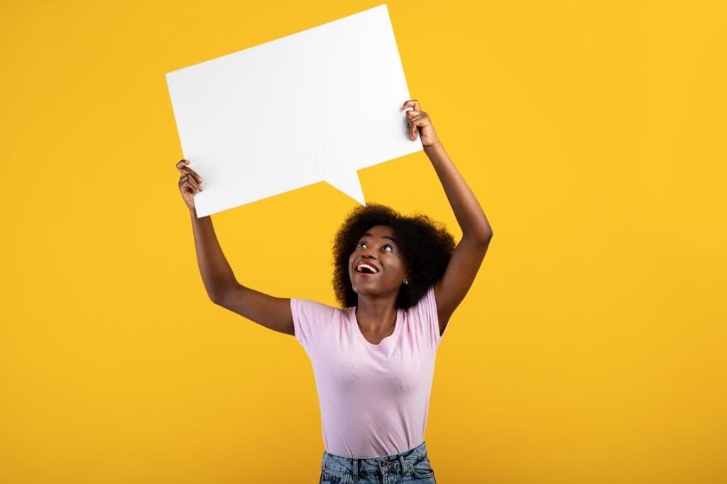 Modern woman holding blank white speech bubble on vibrant yellow background, representing creative communication and digital marketing, ideal for web design and branding services in Durham Region.