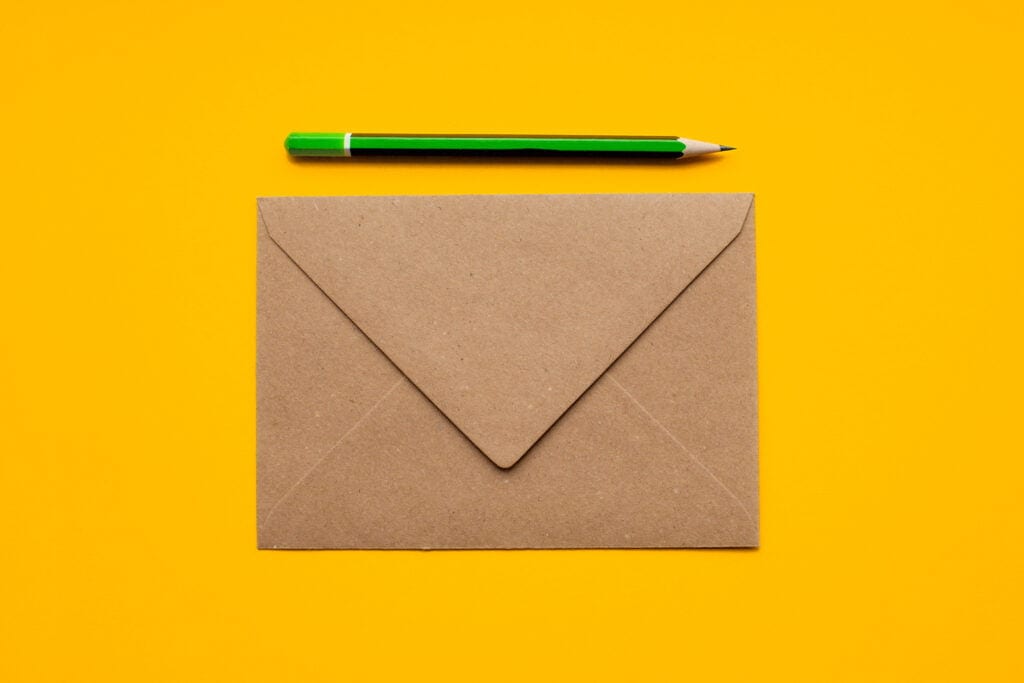 Envelope and green pencil on yellow background, representing professional communication and branding for web design services in Oshawa and Durham Region.