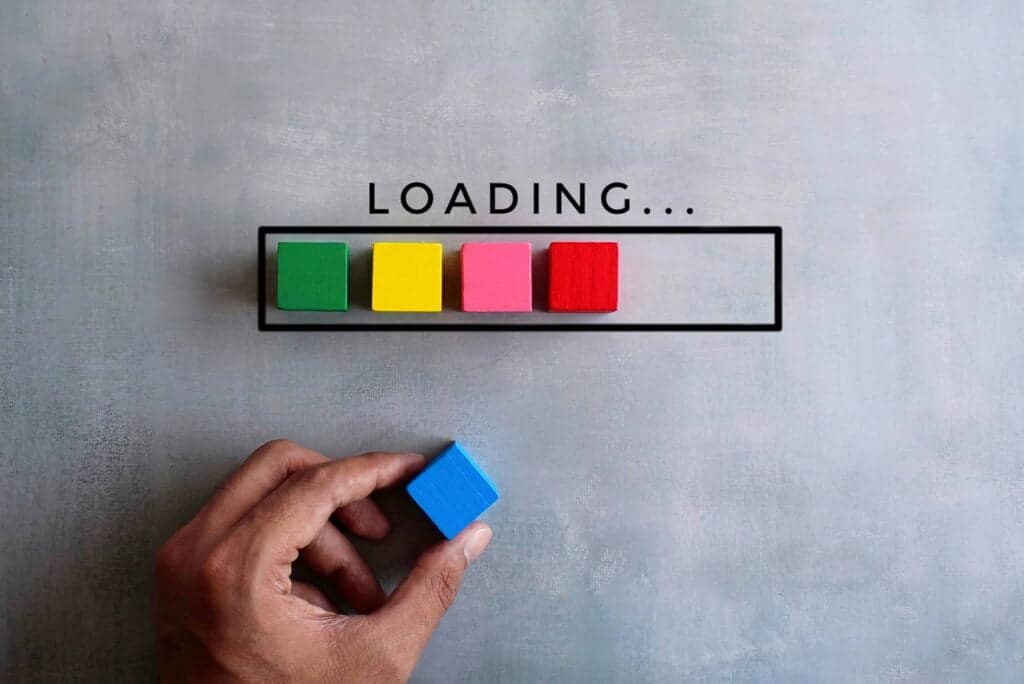 A colorful loading bar with wooden blocks in green, yellow, pink, and red on a light grey background, symbolizing website progress or development.