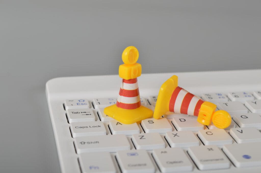 Yellow and orange traffic cone toys on white keyboard close-up.