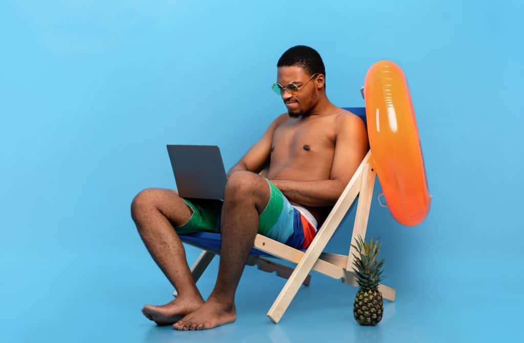 Relaxing man in sunglasses using a laptop on a beach chair, summer scene with pineapple, sunny, leisure, digital nomad lifestyle, beach vacation, summer leisure, tropical, outdoor, casual recording.