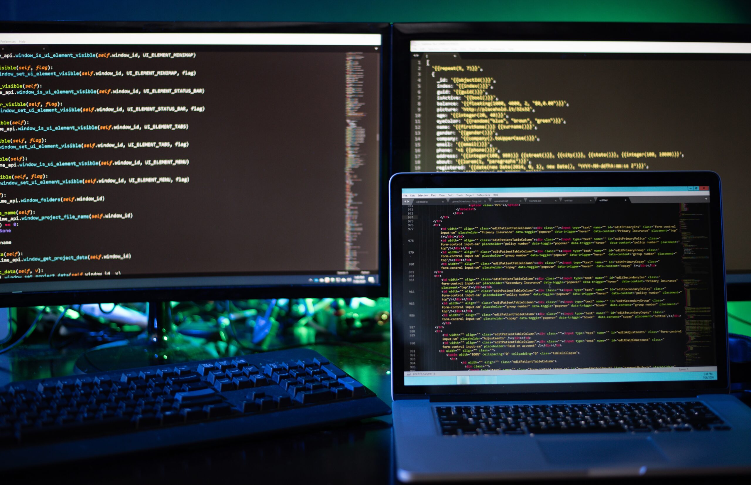 Two computer screens and a laptop displaying code and programming scripts for web development and security.