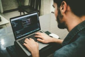 A web developer working on a laptop with coding software open, focusing on website development in a modern office setting.