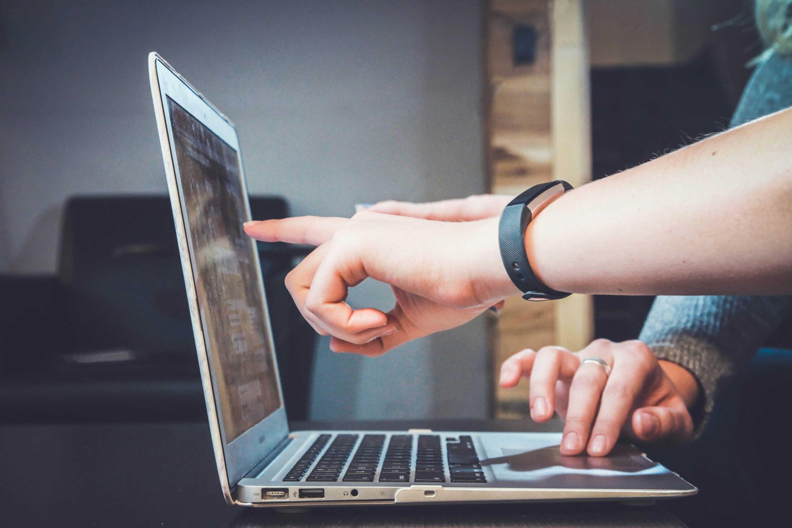 Person pointing at a laptop screen while working on web design, showcasing a digital workspace.